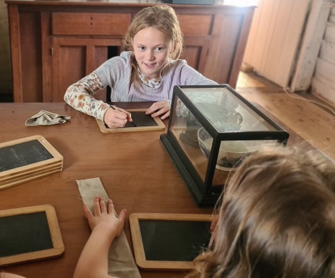 Students writing on slates in Kerikeri Mission House, Kerikeri. Image: LEARNZ.